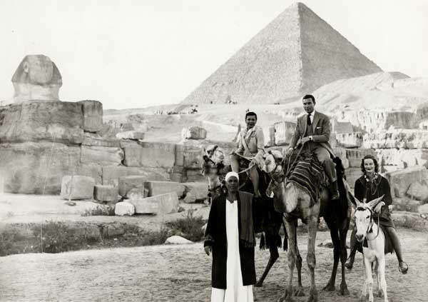 Katherine Dunham on a camel and two others and a guide at the pyramids and Sphinx in Egypt, 1949.